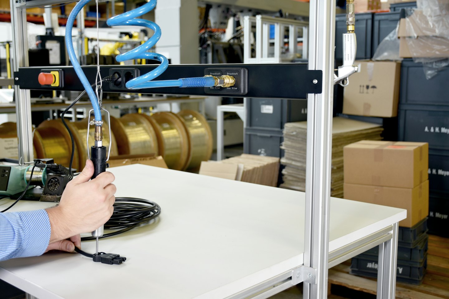 Manos usan una herramienta neumática para ensamblar un componente electrónico.