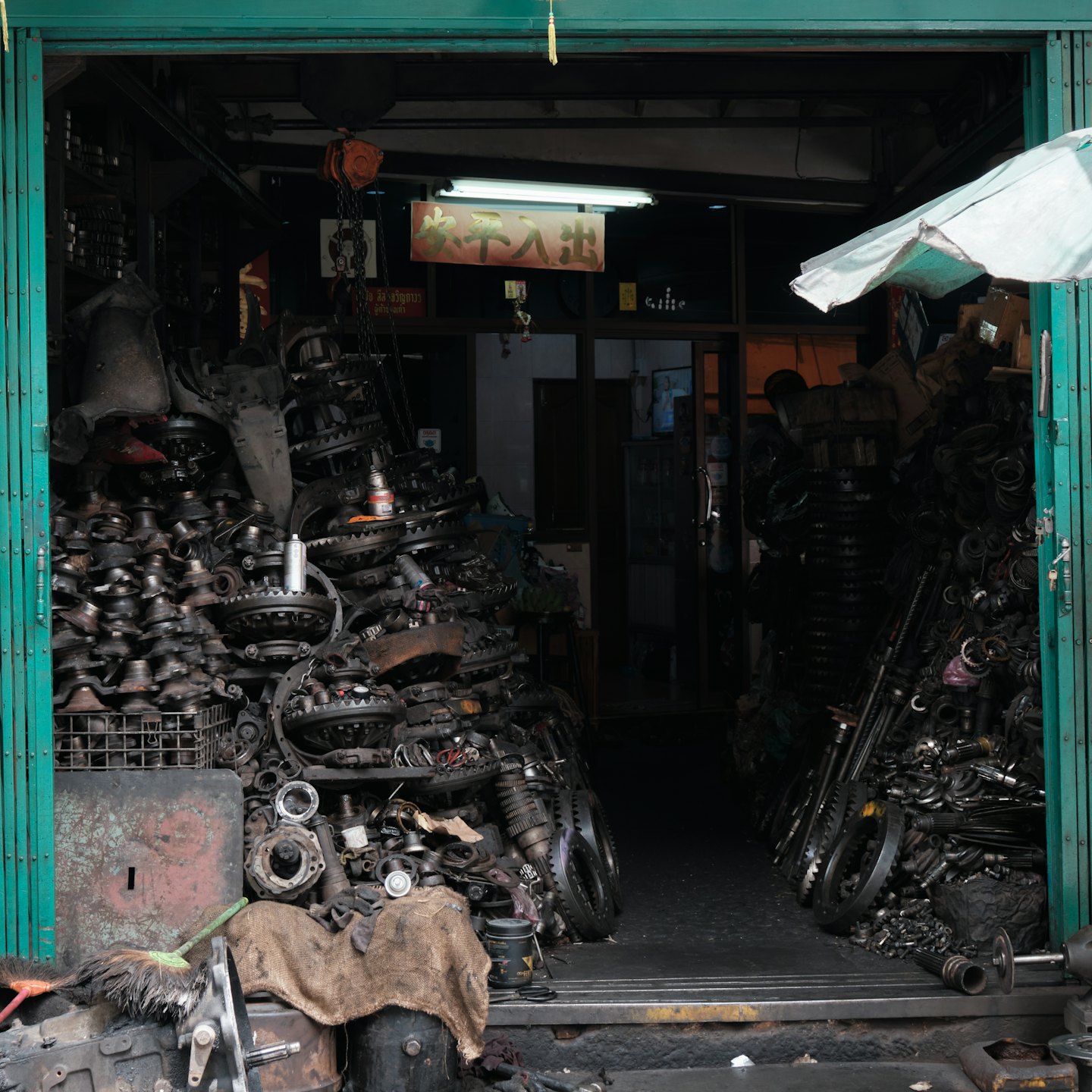 Interior desordenado de una tienda de repuestos de automóviles con pilas de componentes de motor.