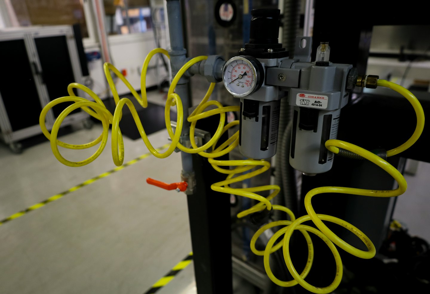 Equipos neumáticos con manómetro y mangueras amarillas en una fábrica.