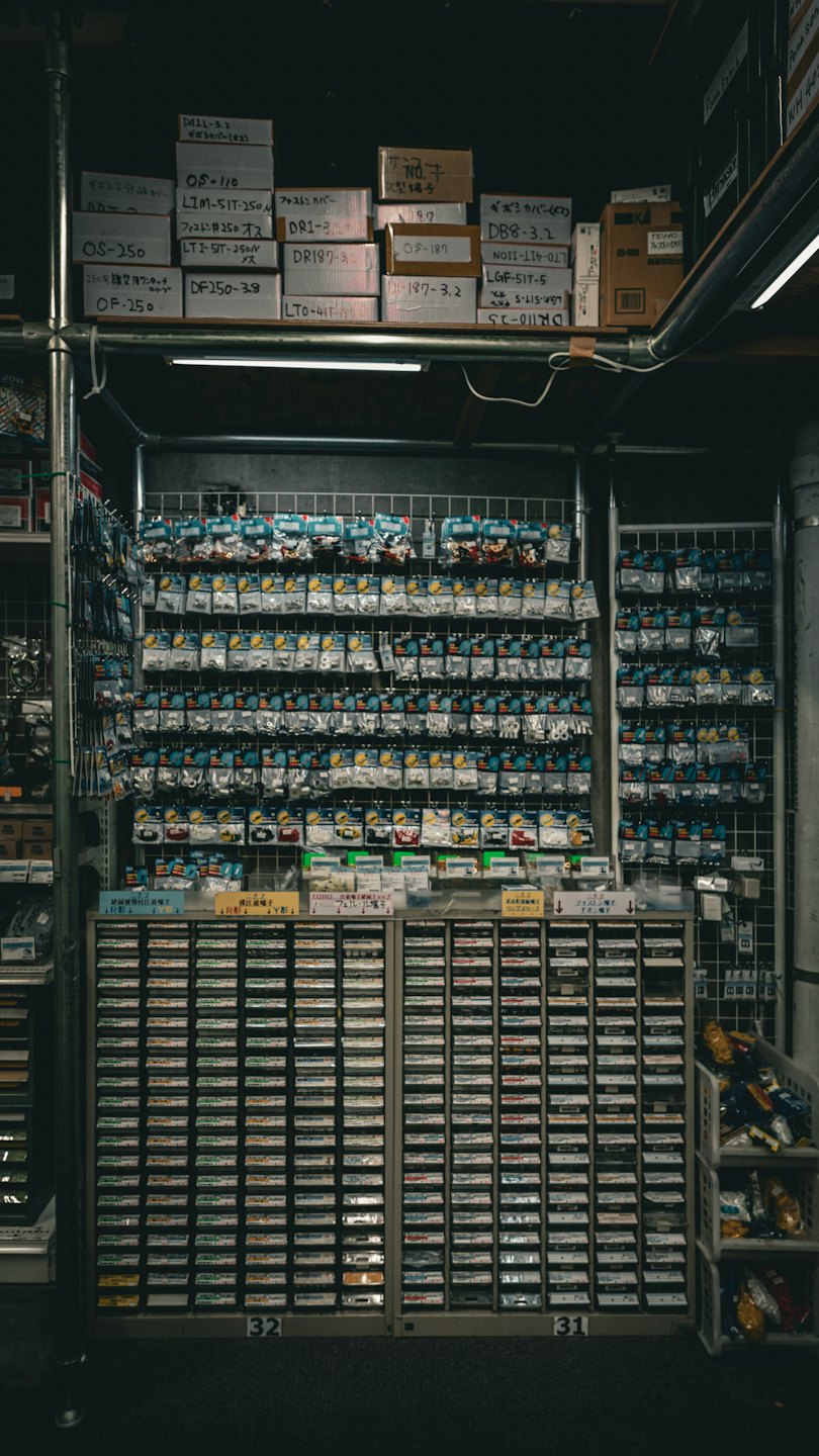Pequeñas piezas electrónicas organizadas en bolsas de plástico en una pared de rejilla.